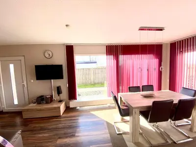 a dining room with a table and chairs and a tv at Ferienpark Vislust Modernes Holzhaus am Ijsselmeer mit eigenen Steg in Wervershoof