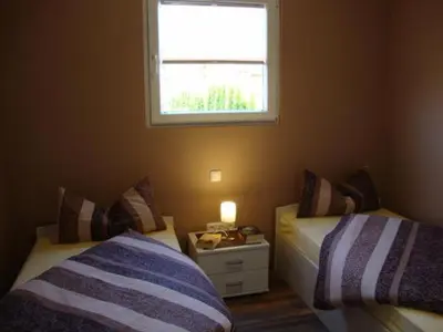 a small bedroom with two beds and a window at Ferienpark Vislust Modernes Holzhaus am Ijsselmeer mit eigenen Steg in Wervershoof