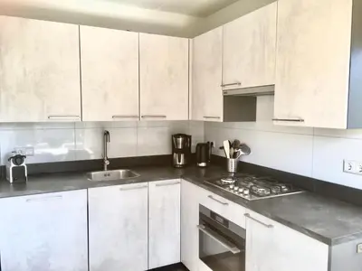 a white kitchen with white cabinets and a sink at Bendalong Noordwijk in Noordwijk