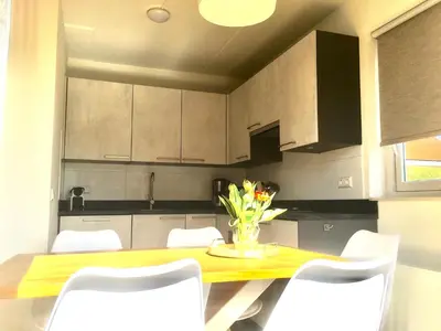 a kitchen with a yellow table and white chairs at Bendalong Noordwijk in Noordwijk