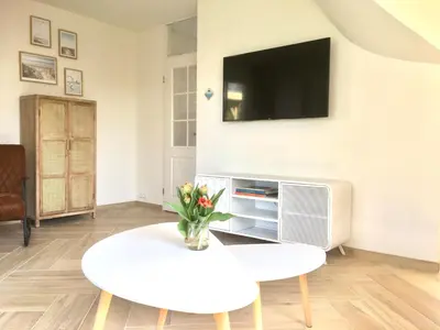 a living room with a white table and a tv at Bendalong Noordwijk in Noordwijk