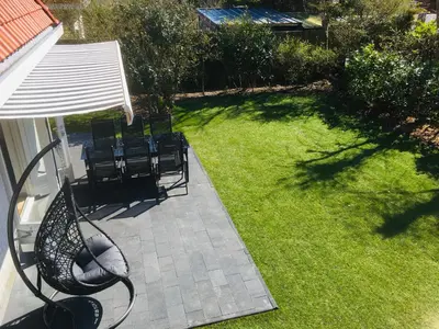 a yard with chairs and a bench and an umbrella at Bendalong Noordwijk in Noordwijk