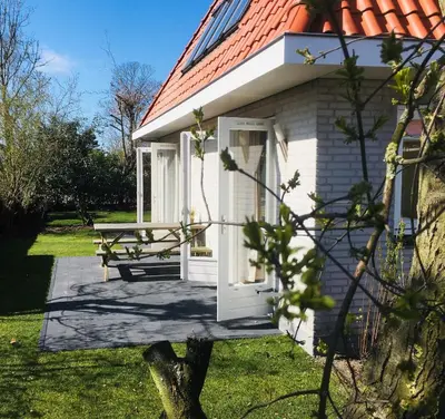 a white house with a picnic table and a bench at Bendalong Noordwijk in Noordwijk
