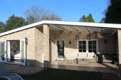 a brick house with a couch and chairs on a patio at Bungalow between Amsterdam and Haarlem with sauna in Vijfhuizen