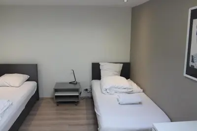 a room with two beds and a night stand with a lamp at Bungalow between Amsterdam and Haarlem with sauna in Vijfhuizen