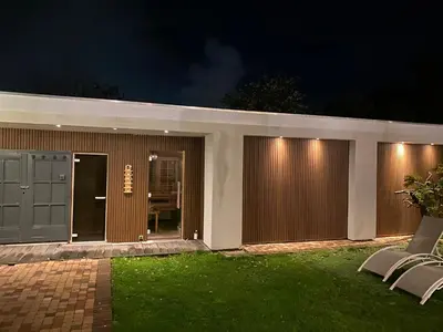 a house with two chairs in the yard at night at Bungalow between Amsterdam and Haarlem with sauna in Vijfhuizen
