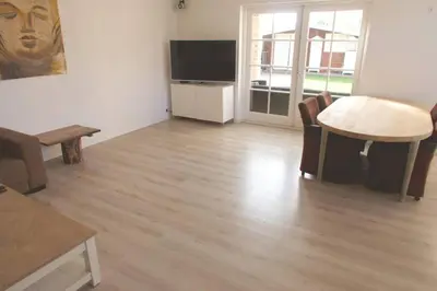 a living room with a table and a television and a table and chairs at Bungalow between Amsterdam and Haarlem with sauna in Vijfhuizen