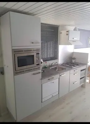 a white kitchen with a microwave and a sink at Cozy chalet in Opmeer near Amsterdam and Beach in Opmeer