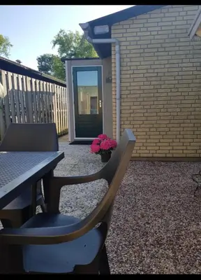 a patio with a table and chairs and flowers at Cozy chalet in Opmeer near Amsterdam and Beach in Opmeer