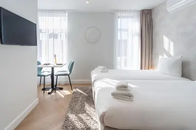 a white hotel room with two beds and a desk at Boutique Hotel At Sea in Zandvoort