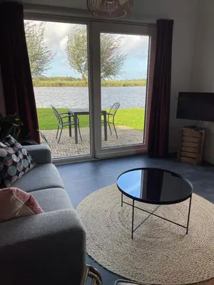 a living room with a couch and a table at Mooi vakantiehuis prachtig gelegen aan het water in Rijpwetering