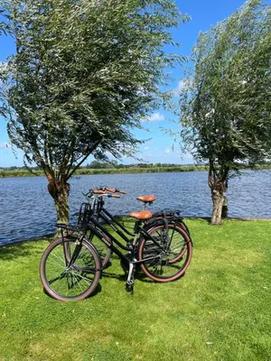 two bikes parked on the grass next to a lake at Mooi vakantiehuis prachtig gelegen aan het water in Rijpwetering