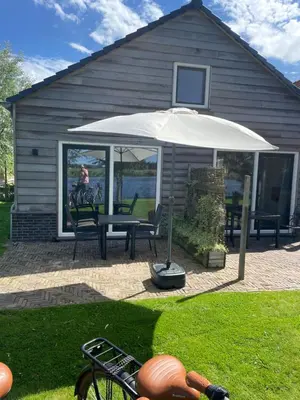 a patio with a table and an umbrella at Mooi vakantiehuis prachtig gelegen aan het water in Rijpwetering