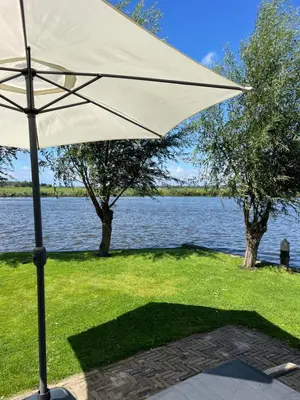 a white umbrella sitting next to a body of water at Mooi vakantiehuis prachtig gelegen aan het water in Rijpwetering
