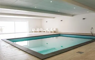 a swimming pool in a room with white chairs at Thalatta in Noordwijk