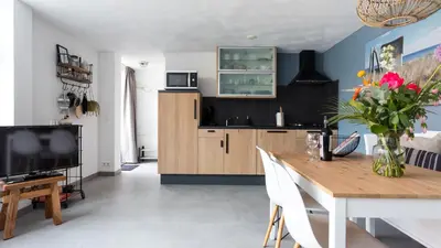 a kitchen and dining room with a table and a tv at HuisjehurenEgmond in Egmond aan Zee