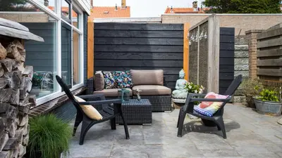 a patio with chairs and a table and a couch at HuisjehurenEgmond in Egmond aan Zee