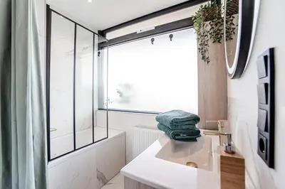 a white bathroom with a sink and a window at Shell 61 in Zandvoort