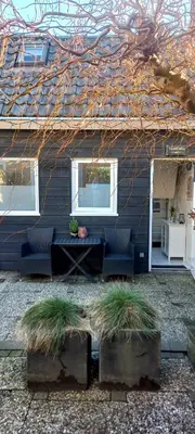 a house with two chairs and a table and windows at 't Koerhaus in Egmond aan Zee