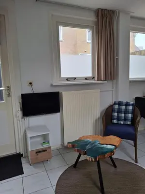 a living room with a chair and a tv at 't Koerhaus in Egmond aan Zee