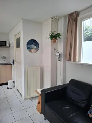 a living room with a black couch and a window at 't Koerhaus in Egmond aan Zee