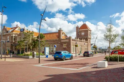 a blue car parked in front of a building with a clock tower at The New Fisherman’s House in Zandvoort