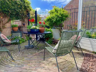 a patio with two chairs and a table with flowers at The New Fisherman’s House in Zandvoort