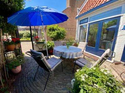 a patio with a table and chairs with a blue umbrella at The New Fisherman’s House in Zandvoort