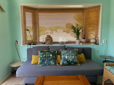 a couch in a living room with a window at Summer house on the Dutch coast in IJmuiden