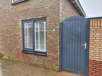 a brick building with a blue door and a window at Knus huisje met prachtige nieuwe badkamer - Distelhoek in Egmond aan Zee