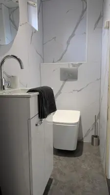 a white bathroom with a sink and a toilet at Knus huisje met prachtige nieuwe badkamer - Distelhoek in Egmond aan Zee