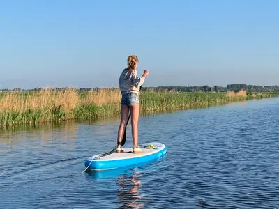 a woman standing on a paddle board in the water at Boerencamping Swarthoeve in Wormer