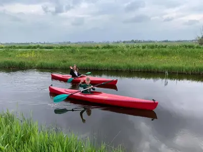 two people in red kayaks on a river at Boerencamping Swarthoeve in Wormer