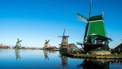 a group of windmills next to a river with buildings at Boerencamping Swarthoeve in Wormer