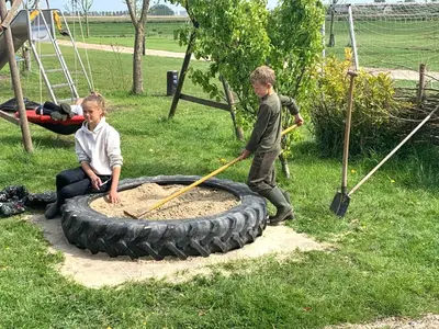 two young boys playing with a tire in the yard at Boerencamping Swarthoeve in Wormer
