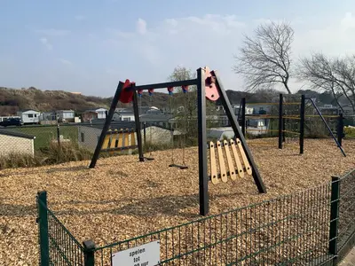 a swing set with bats on it in a park at Chalet Playa direct aan zee in IJmuiden in IJmuiden