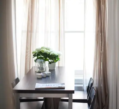 a table with a vase of flowers on it next to a window at Darley's in Hilversum