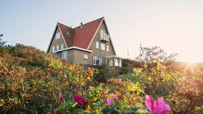 a house on top of a hill with flowers at Villa Parnassia in Bergen aan Zee