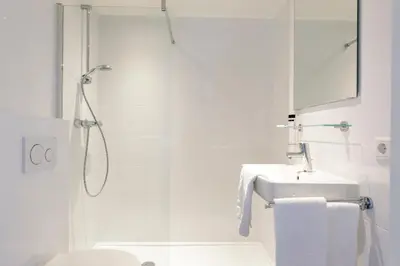 a white bathroom with a shower and a sink at Villa Parnassia in Bergen aan Zee