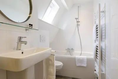 a bathroom with a sink and a toilet and a mirror at Villa Parnassia in Bergen aan Zee