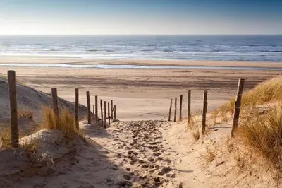 a sandy beach with a fence and the ocean at Villa Parnassia in Bergen aan Zee