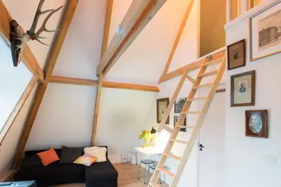 a loft conversion with a ladder and a couch at At the Butchers in Amsterdam