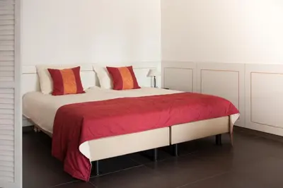 a white bedroom with a large bed with red pillows at Newhouse Logies in Zevenhoven