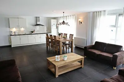 a living room with a couch a table and a kitchen at Newhouse Logies in Zevenhoven