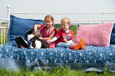 two young children sitting on a bed with a dog at Newhouse Logies in Zevenhoven