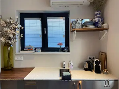 a kitchen with a counter with a sink and two windows at Houseboat Sophia in Amsterdam