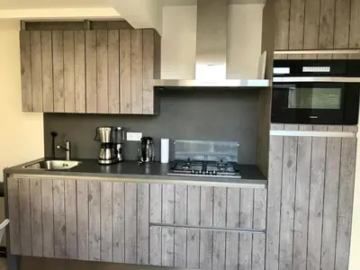 a kitchen with wooden cabinets and a stove top oven at Ferienhaus Genießen am Meer mit Wellnesszugang in Egmond aan Zee
