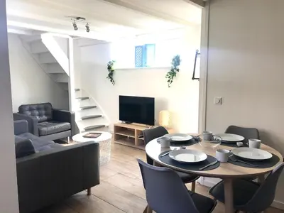 a living room with a table and chairs and a television at Ferienhaus Genießen am Meer mit Wellnesszugang in Egmond aan Zee