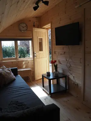 a living room with a couch and a tv on a wall at Polderlodge in Hillegom