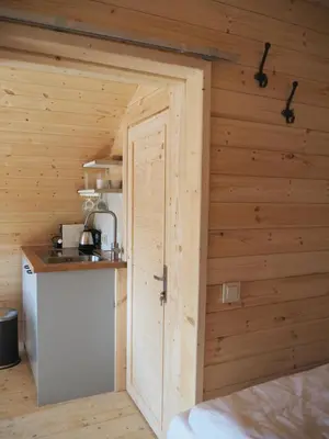 a small kitchen with a door in a wooden wall at Polderlodge in Hillegom